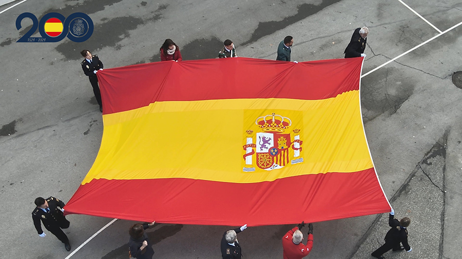 Agentes de la Policía Nacional portando la Bandera de España en el acto de izado.